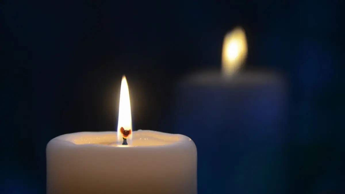 A single lit candle glowing softly against a dark blue background