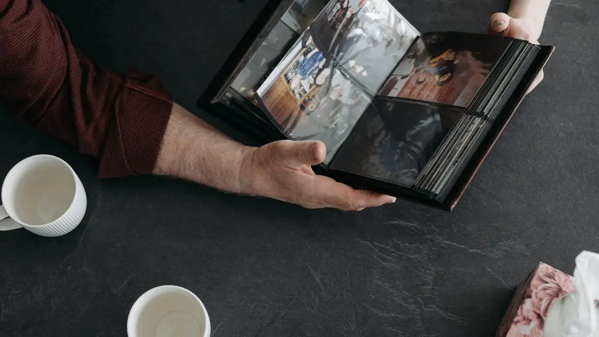 Hands holding an open photo album over a dark table
