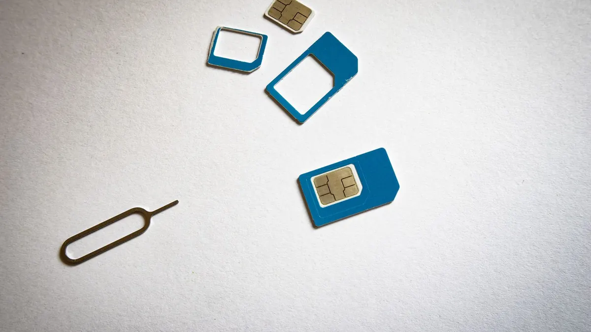 SIM cards and a SIM ejector tool on a white surface