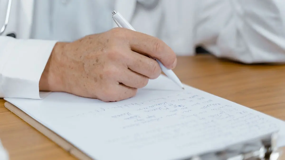 A hand writing a list on paper with a pen