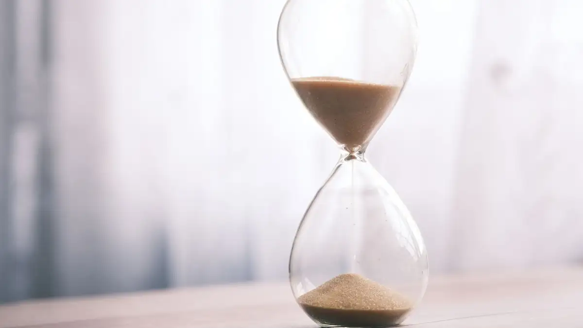 An hourglass on a table by a window in soft light