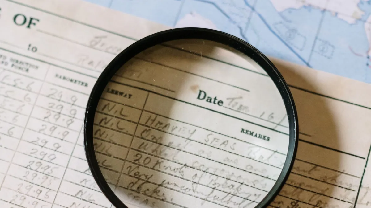 A magnifying glass resting on a handwritten logbook