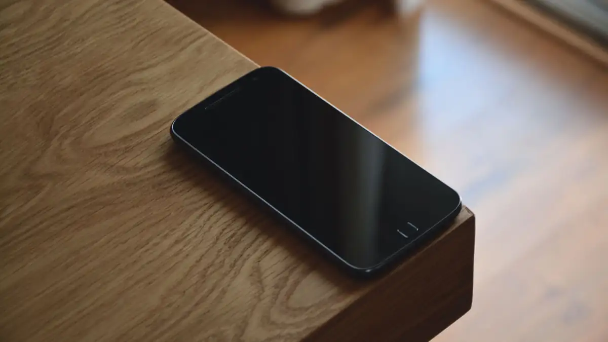 A phone lying dark on a wooden table