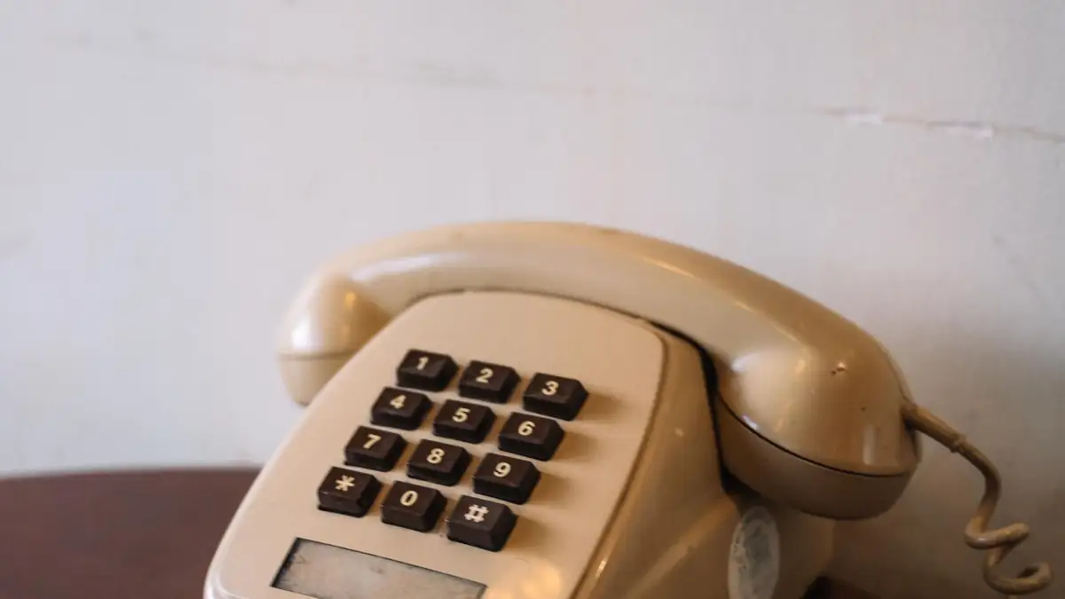 A beige corded telephone on a wooden table