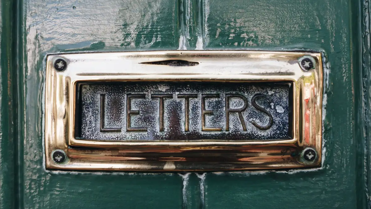 A brass letterbox marked Letters on a green front door