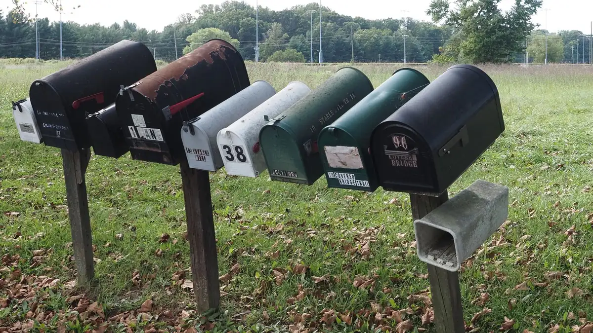 A row of rural mailboxes on wooden posts beside a field