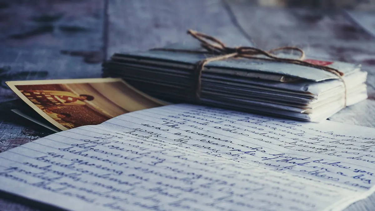 A bundle of old letters tied with string beside a handwritten letter and photographs