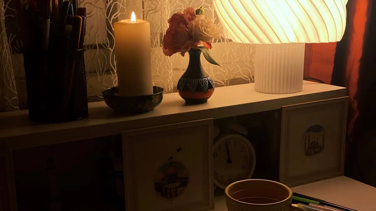 A warm desk lamp, a candle and handwritten notes on a desk